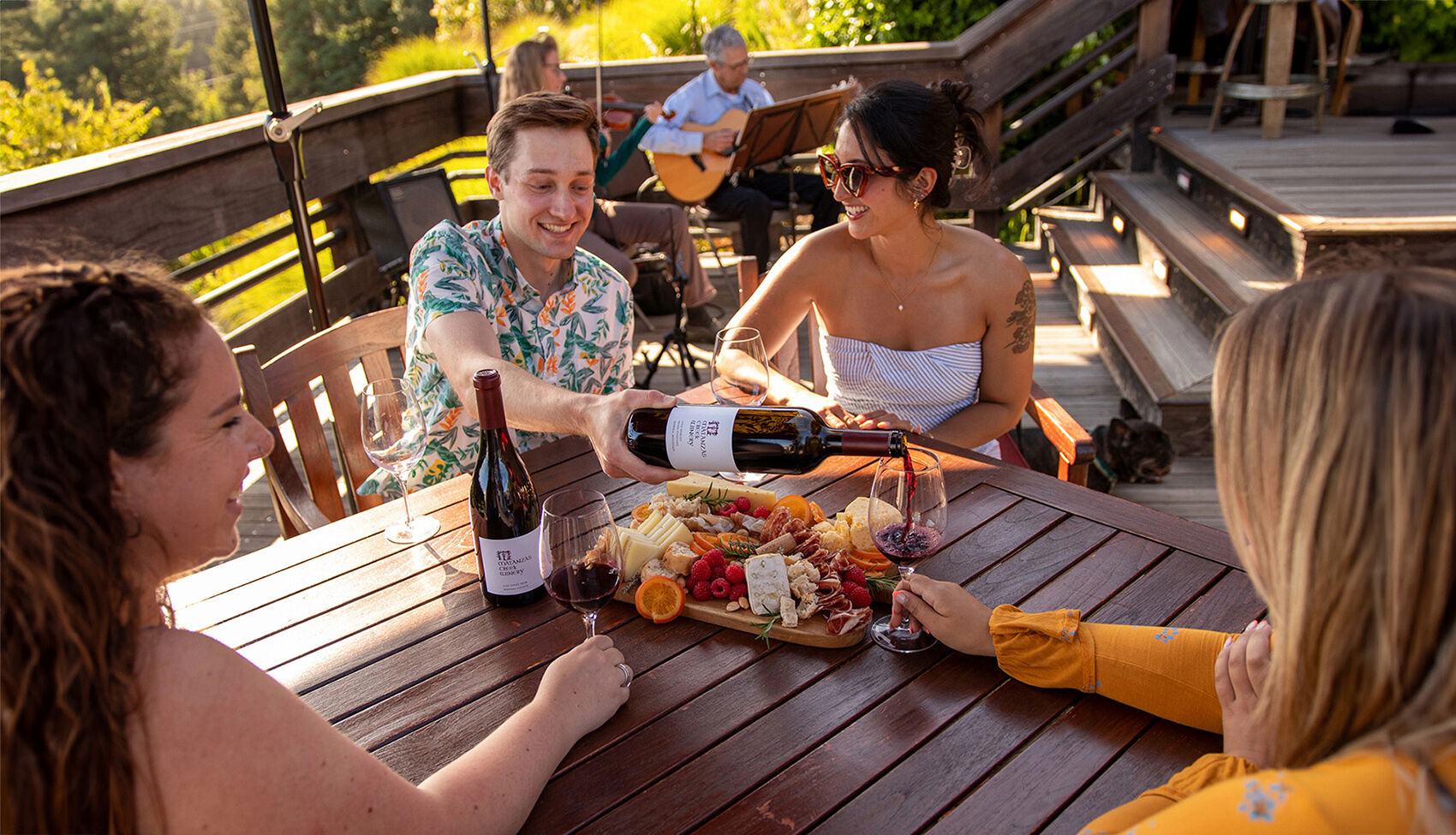 An elevated wood patio with three adirondack chairs on the ground.