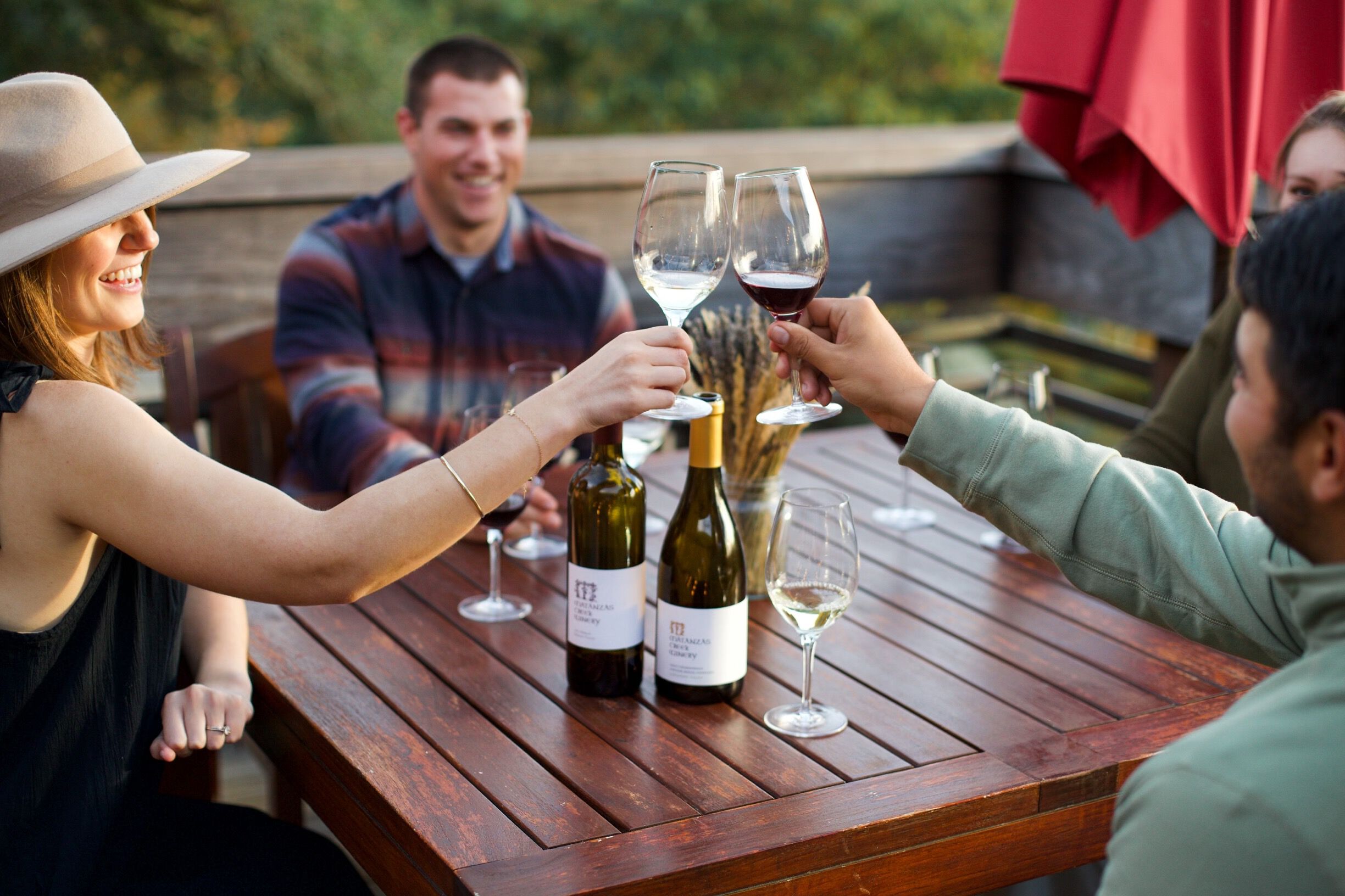 An elevated wood patio with three adirondack chairs on the ground.